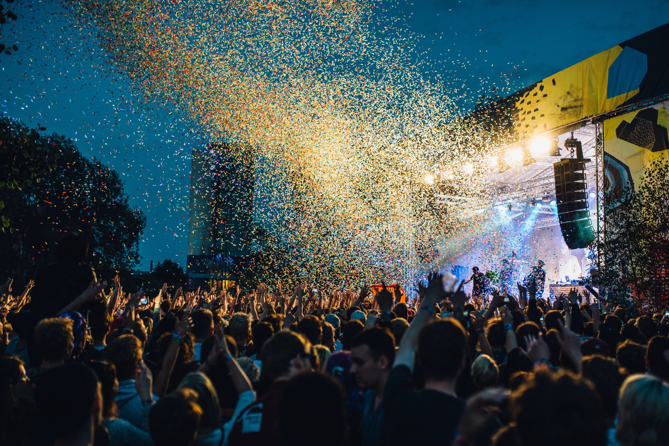 Outdoor concert with stage lights and confetti above the crowd
